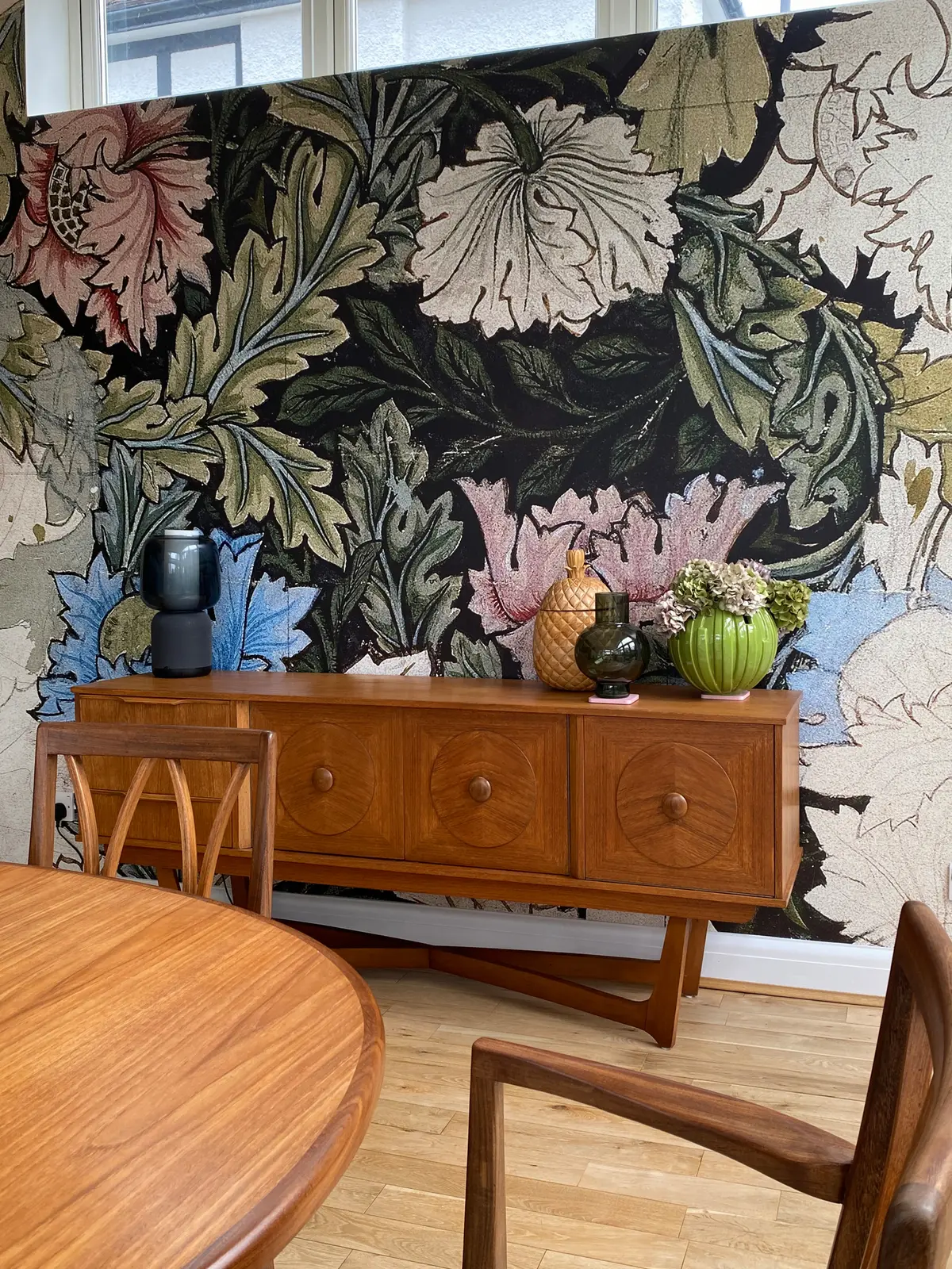 Mid-century teak sideboard against a bold dark floral wallpaper in a New Barnet dining room