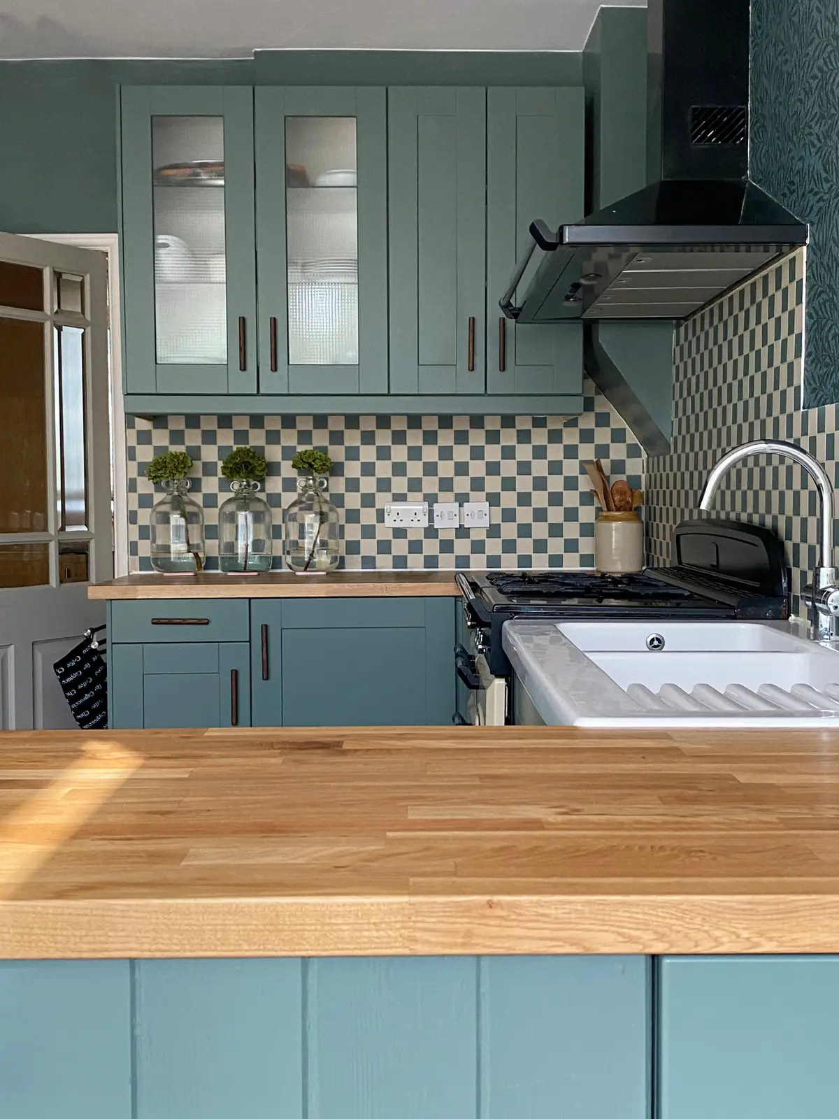Spray-painted blue-grey kitchen with patterned tiles and an oak worktop