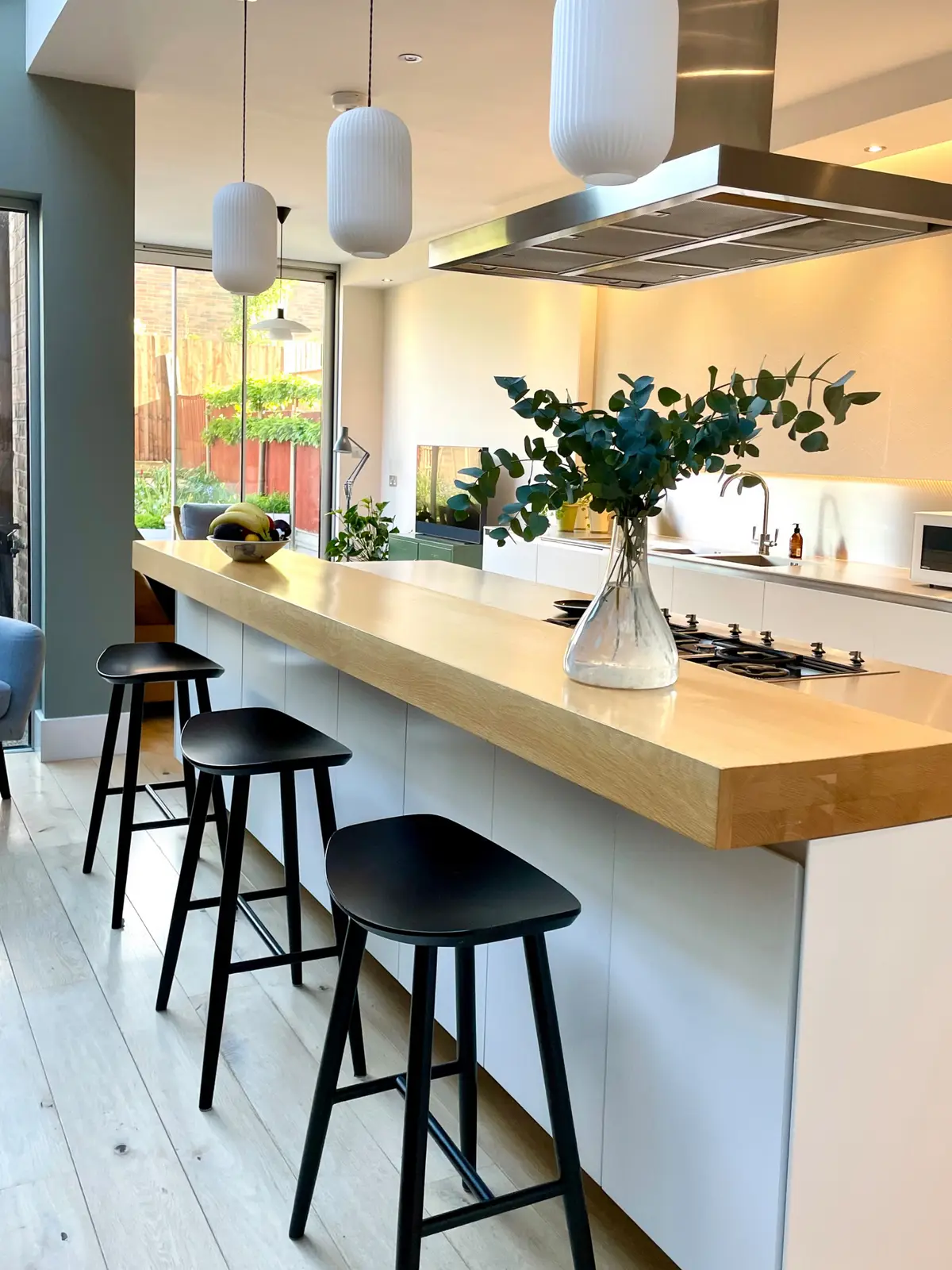 Oak breakfast bar with black stools and a view to the garden