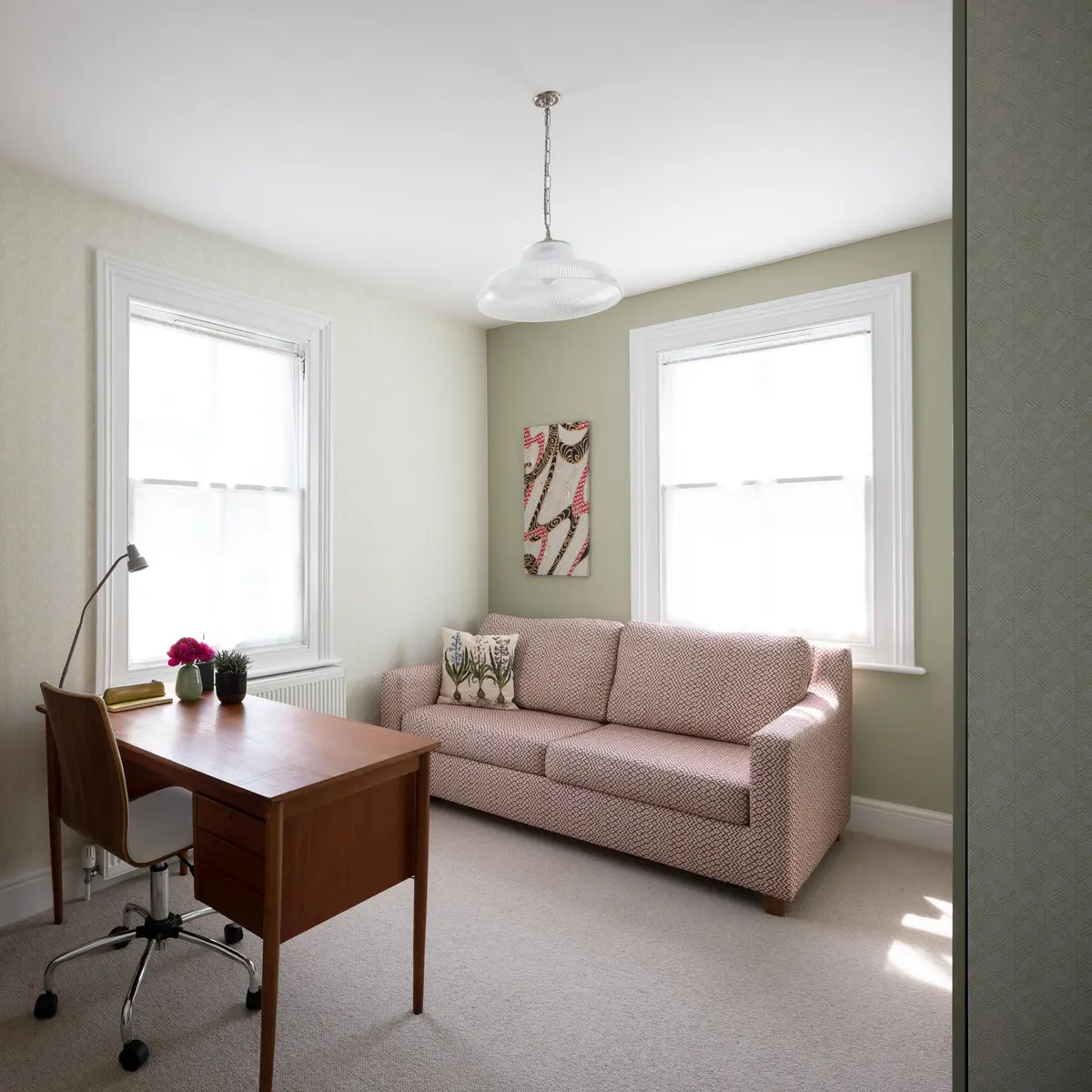 Blush sofa bed and sage walls in a home office and guest room