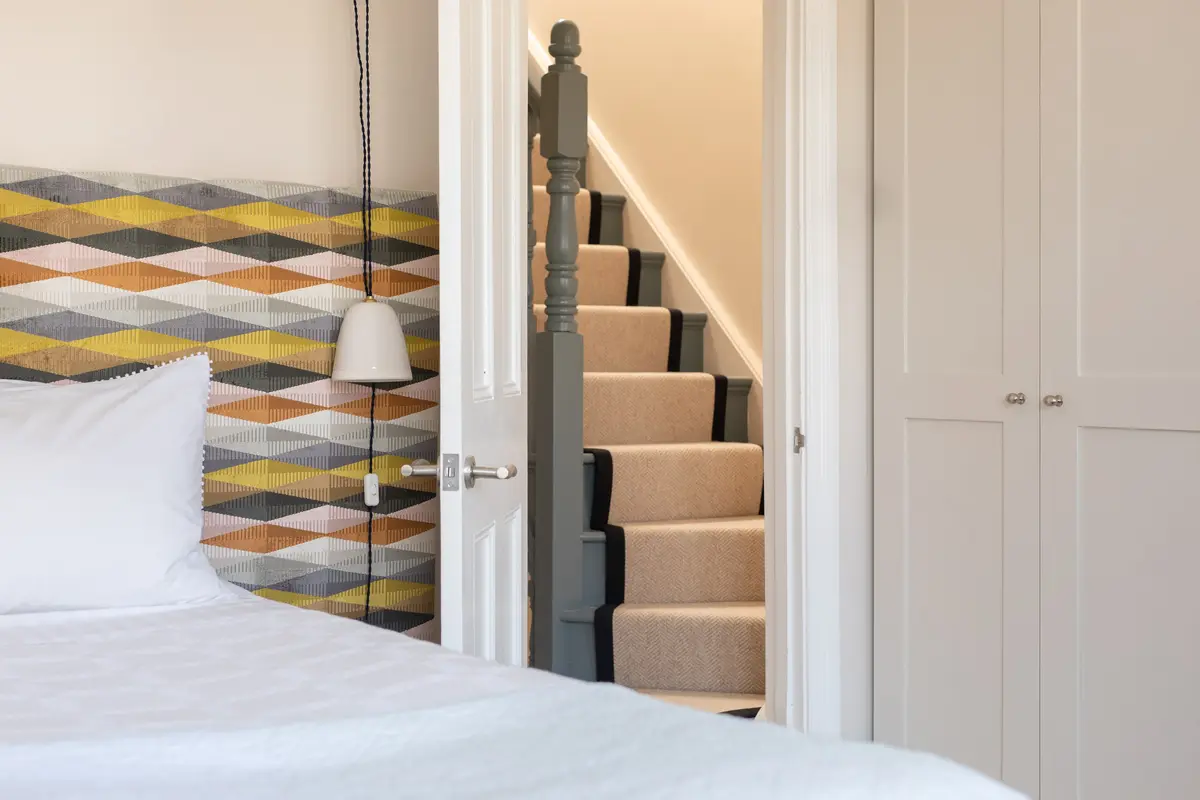 Loft bedroom with a geometric patterned wall and carpeted stair