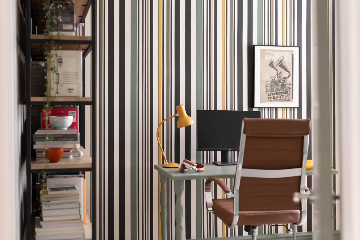 Home office nook with striped wallpaper, desk and bookshelves