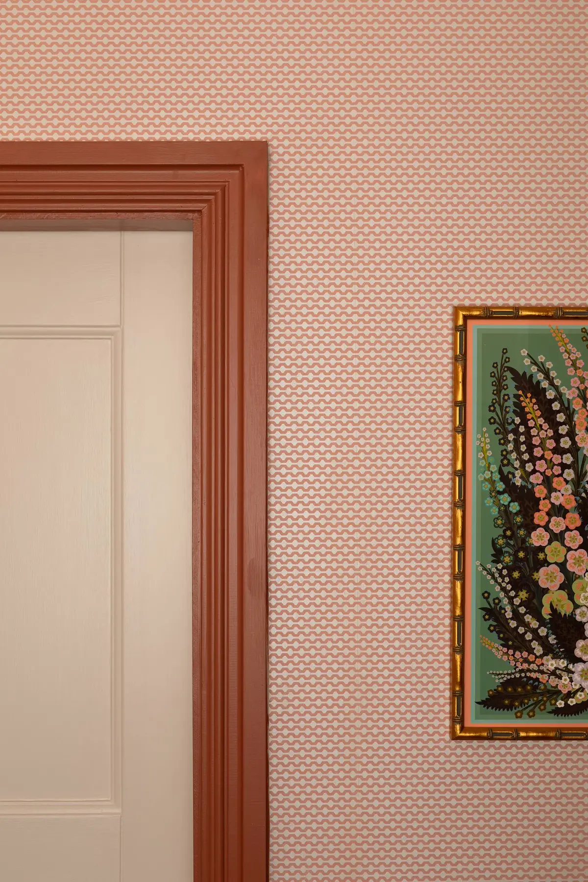 Blush patterned wallpaper and framed botanical artwork in a home office