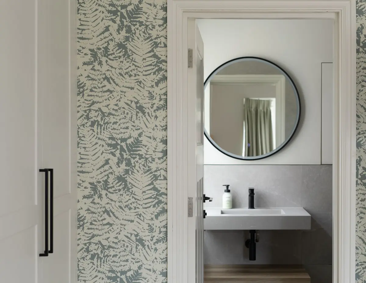 Bathroom with a round mirror, floating basin and leafy wallpaper
