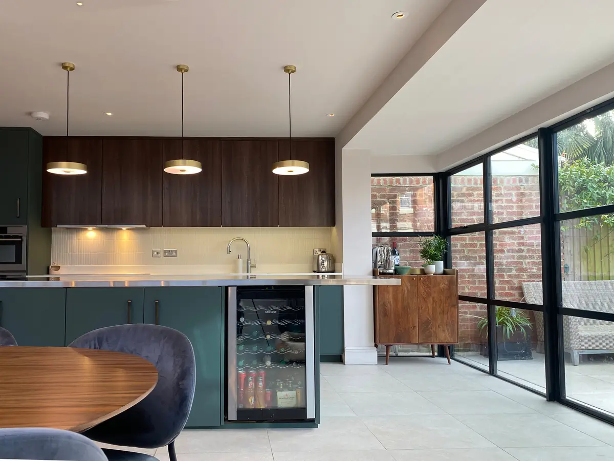 Kitchen-diner with dark timber units, pendant lights and black Crittall-style doors to the garden