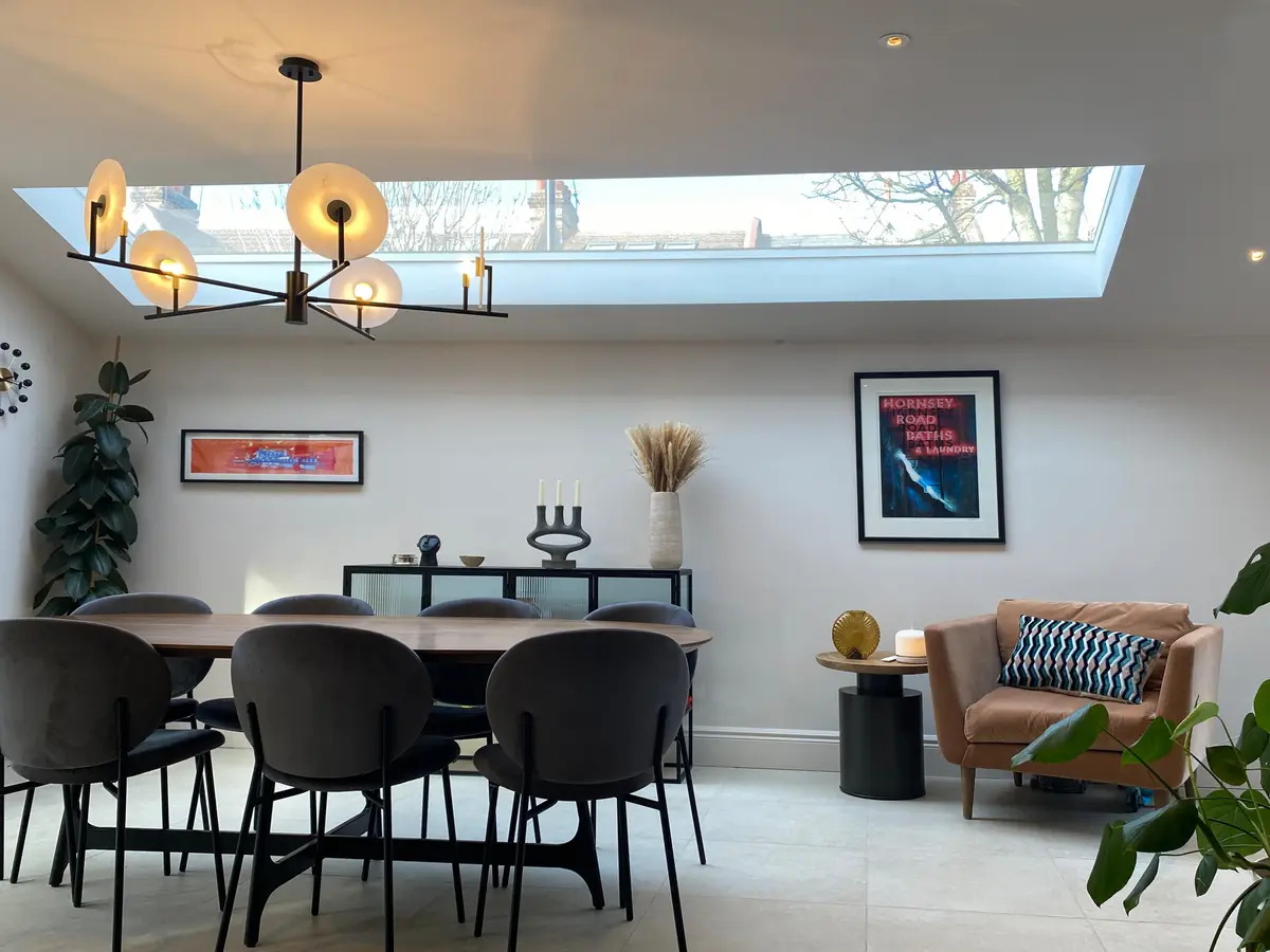Bright dining room with black chairs, a sputnik chandelier and a rooflight