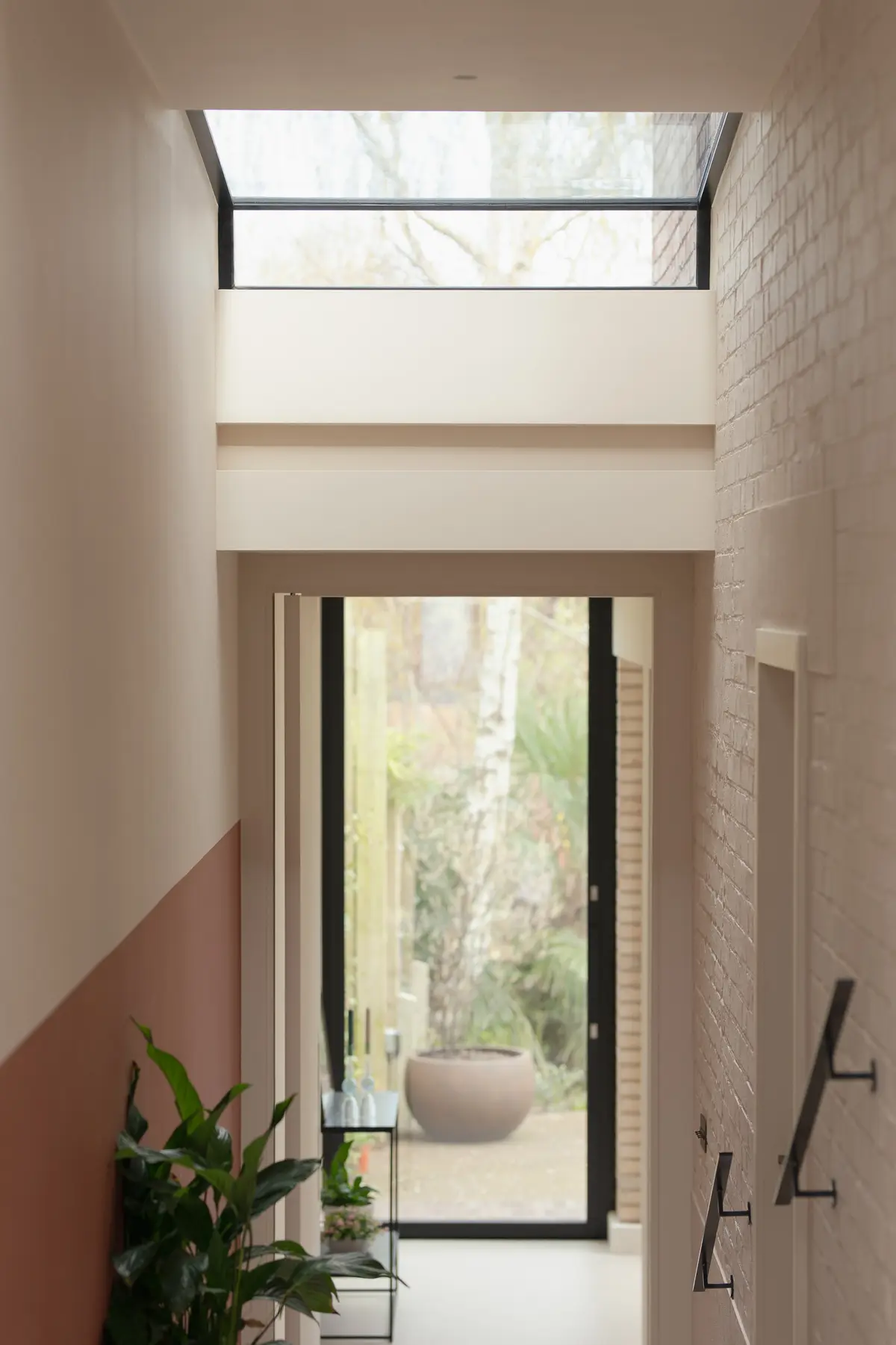 View through a pale hallway with a terracotta-painted dado towards the garden