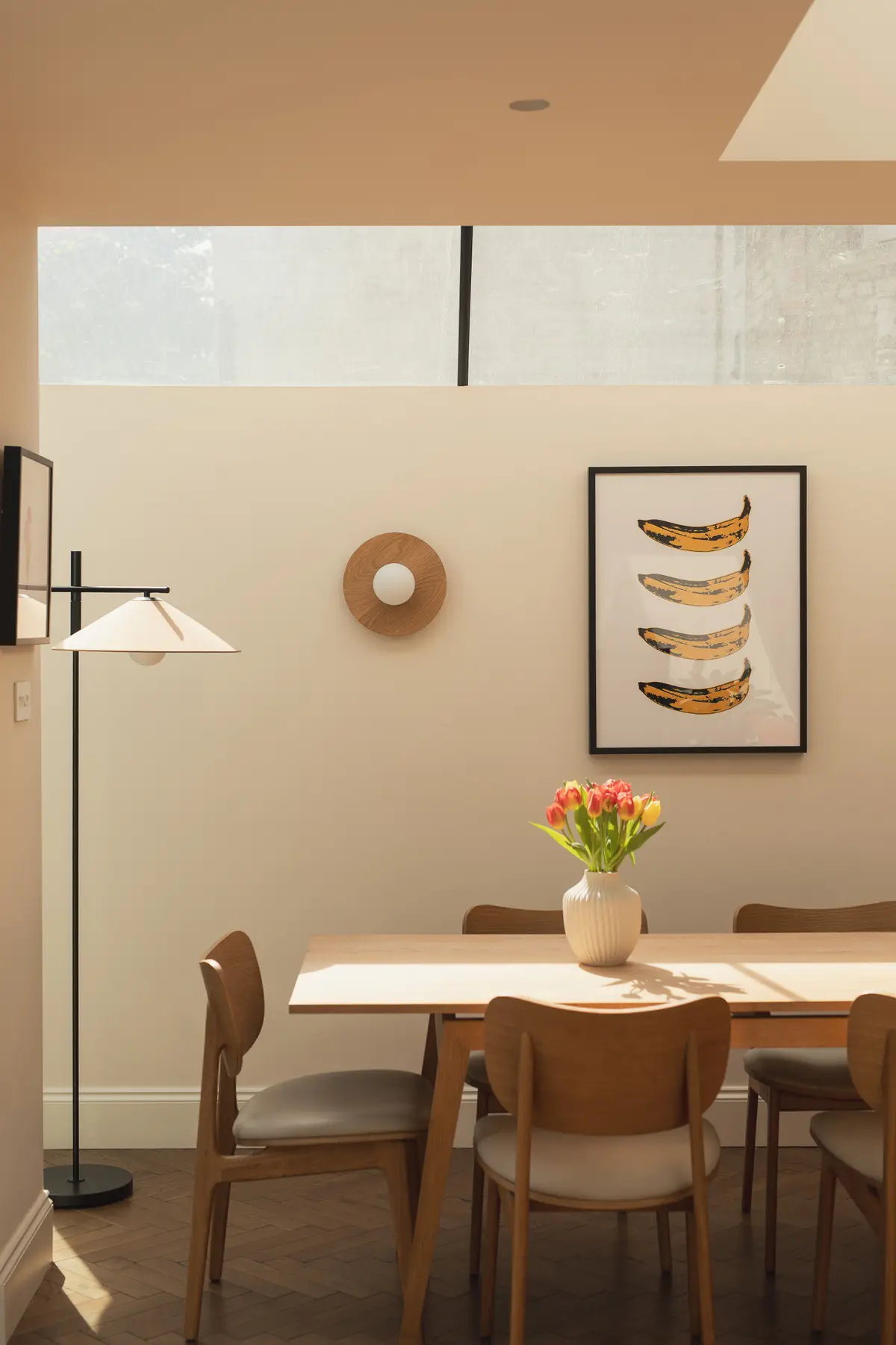 Pleated pendant lamp above a dining table with tulips and a banana print