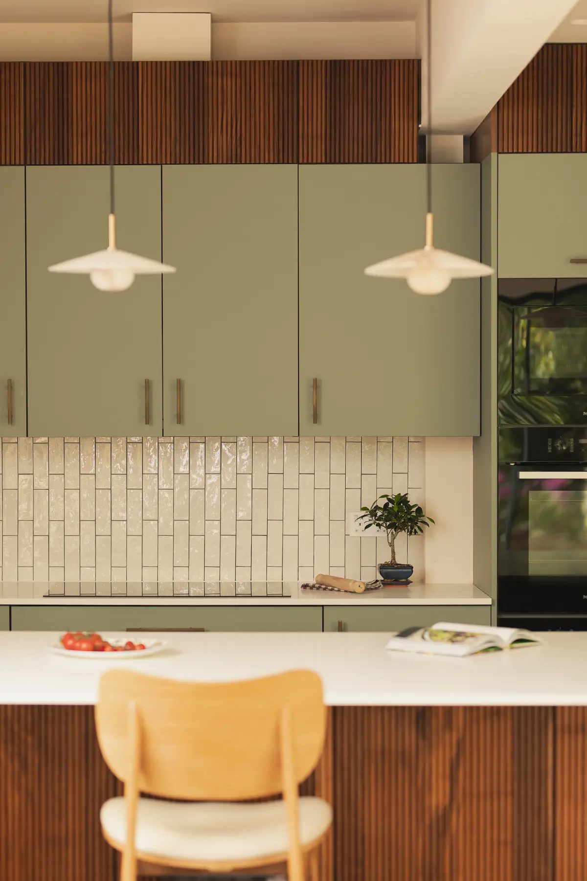Sage green kitchen cabinets with handmade white tiles and an open shelf