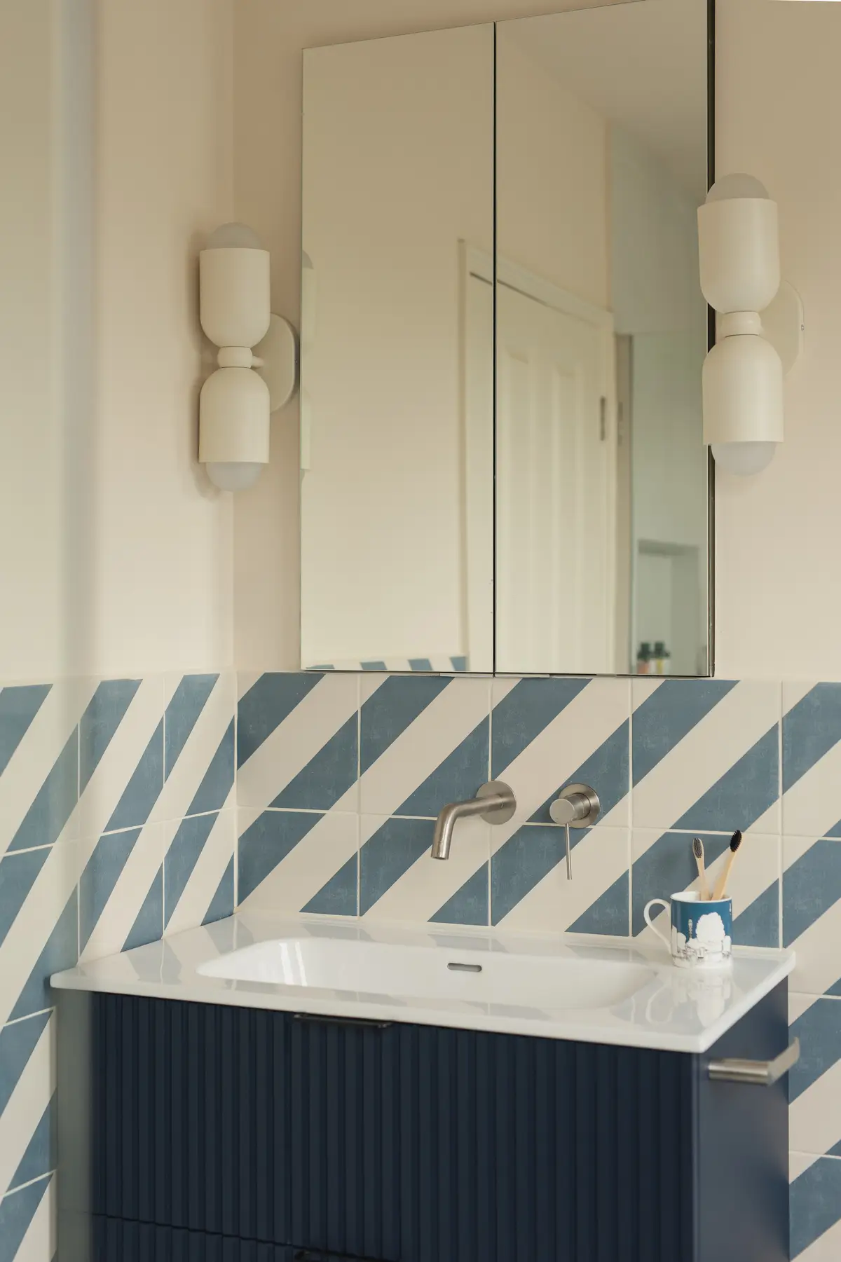 Cloakroom with blue-and-white diagonal striped tiles and a wall-hung basin