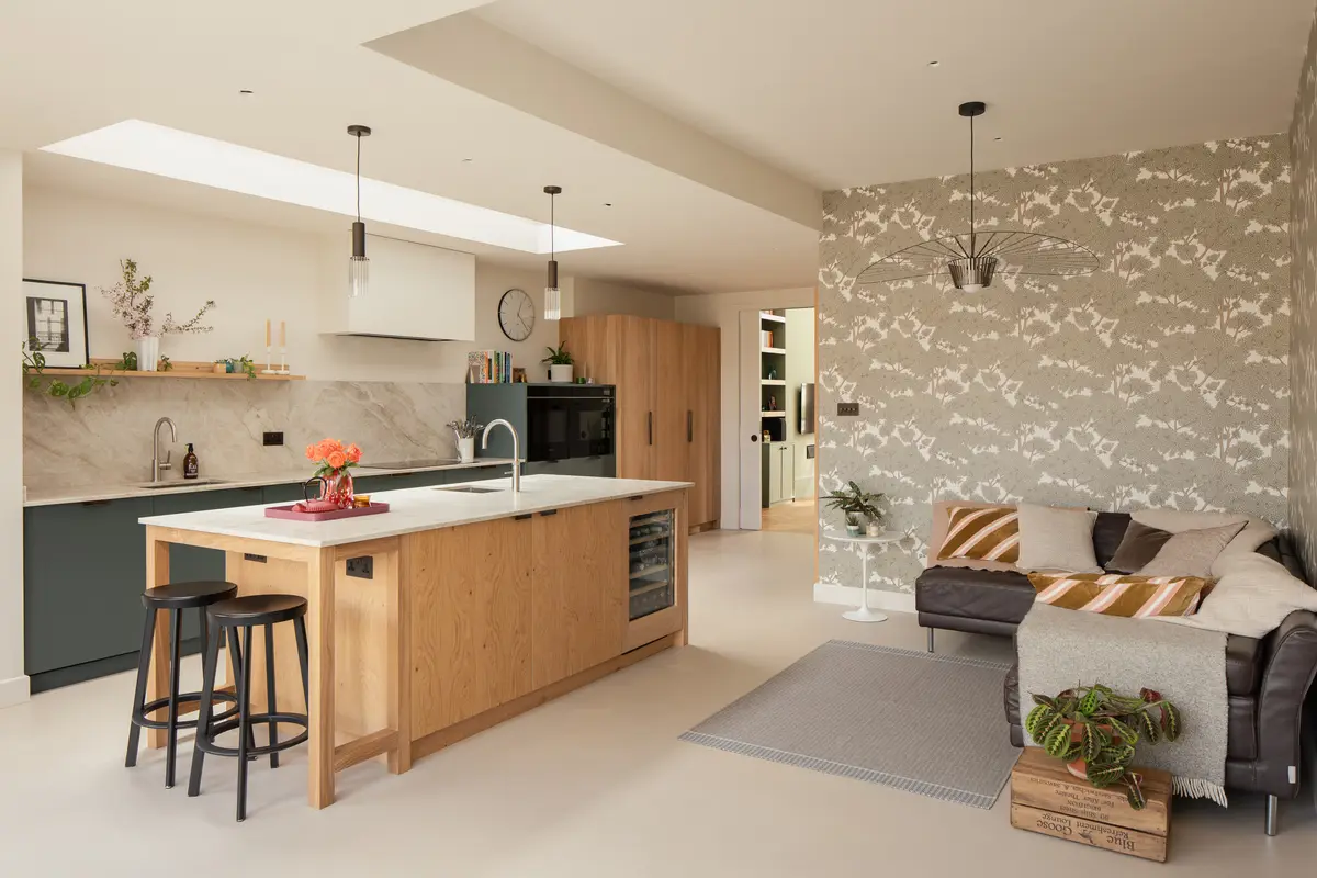 Open kitchen with oak island, bar stools and a botanical wallpaper