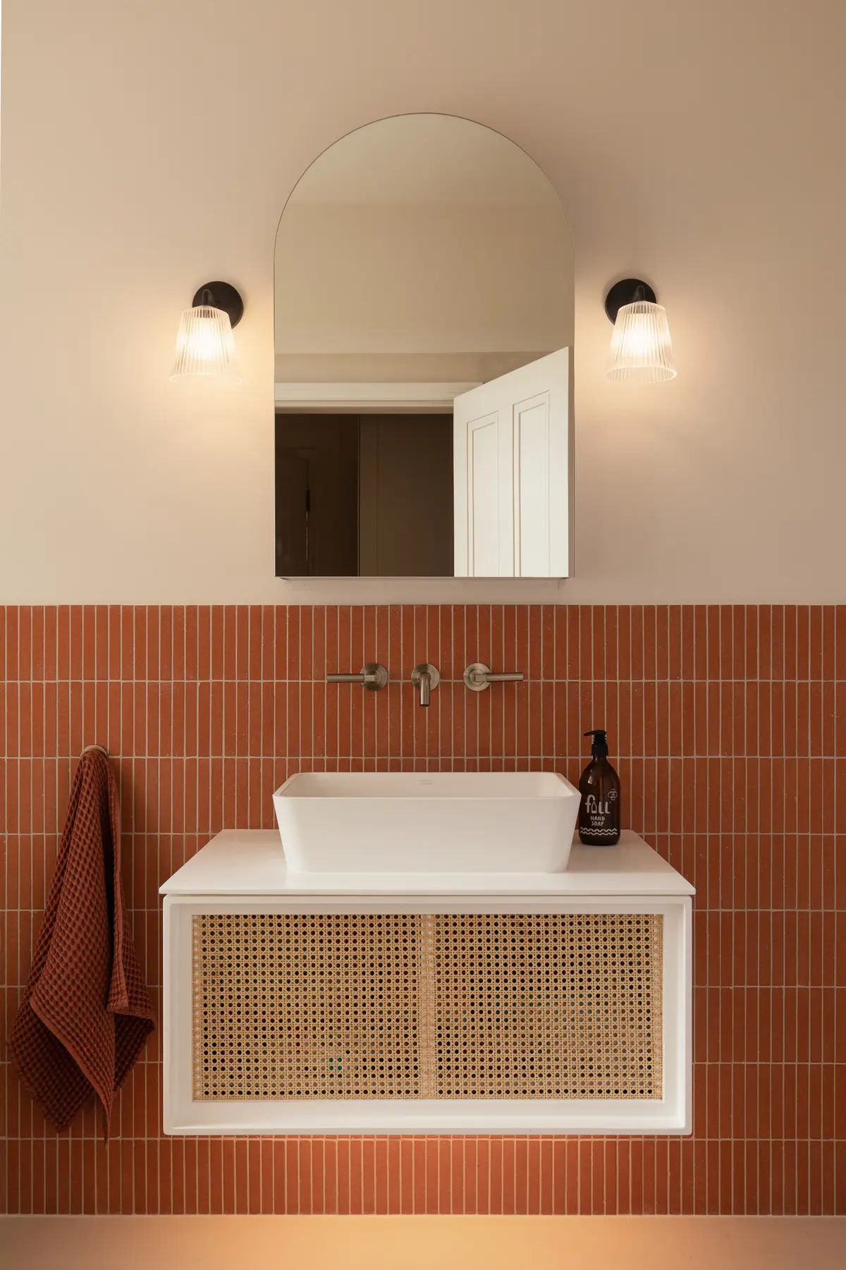 Bathroom with terracotta tiles, a wall-hung basin and brass taps