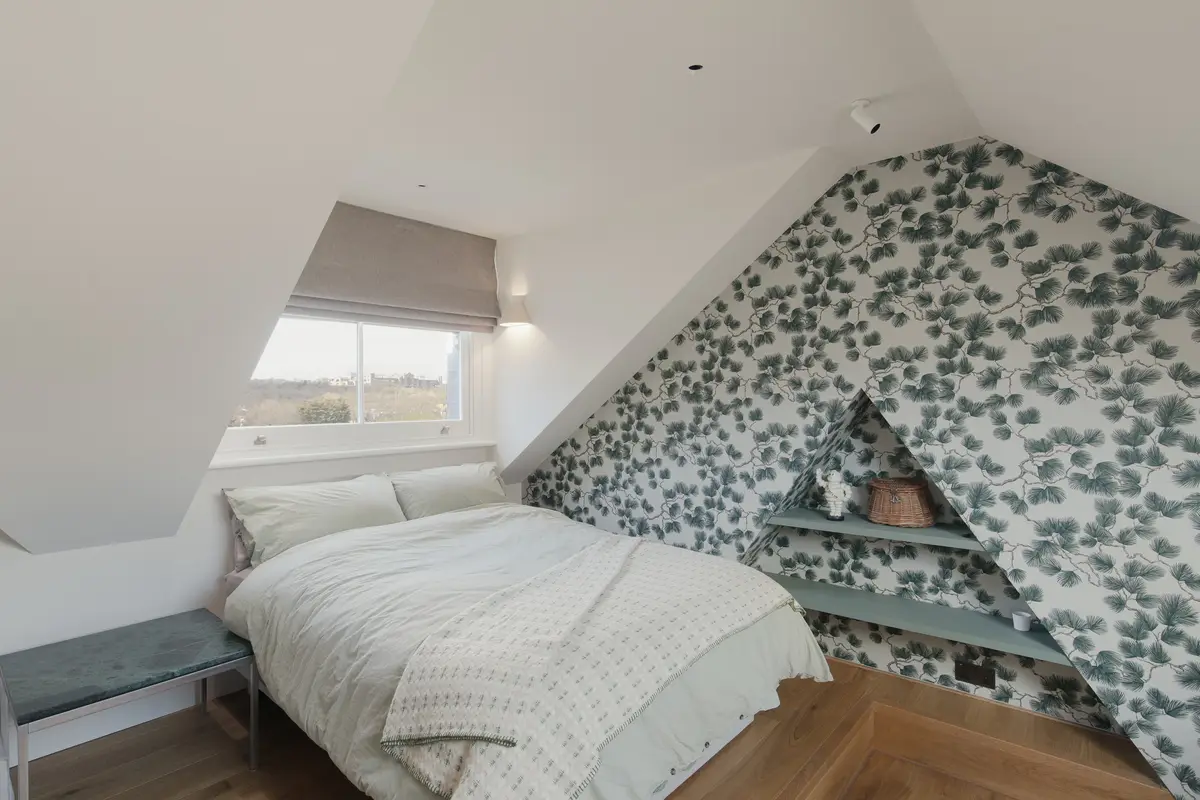 Loft bedroom with leaf-pattern wallpaper across the sloping ceiling