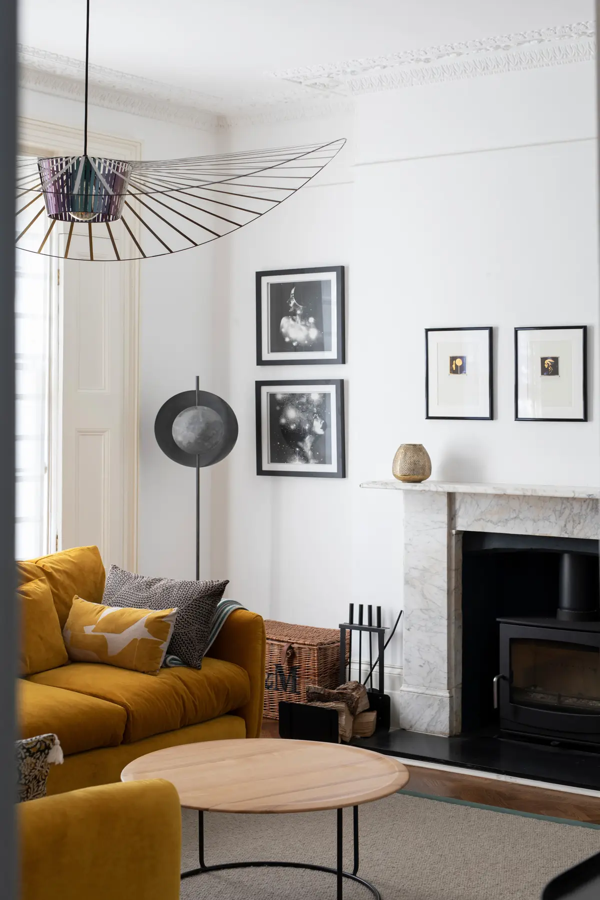 Mustard velvet sofa and side table beneath framed prints