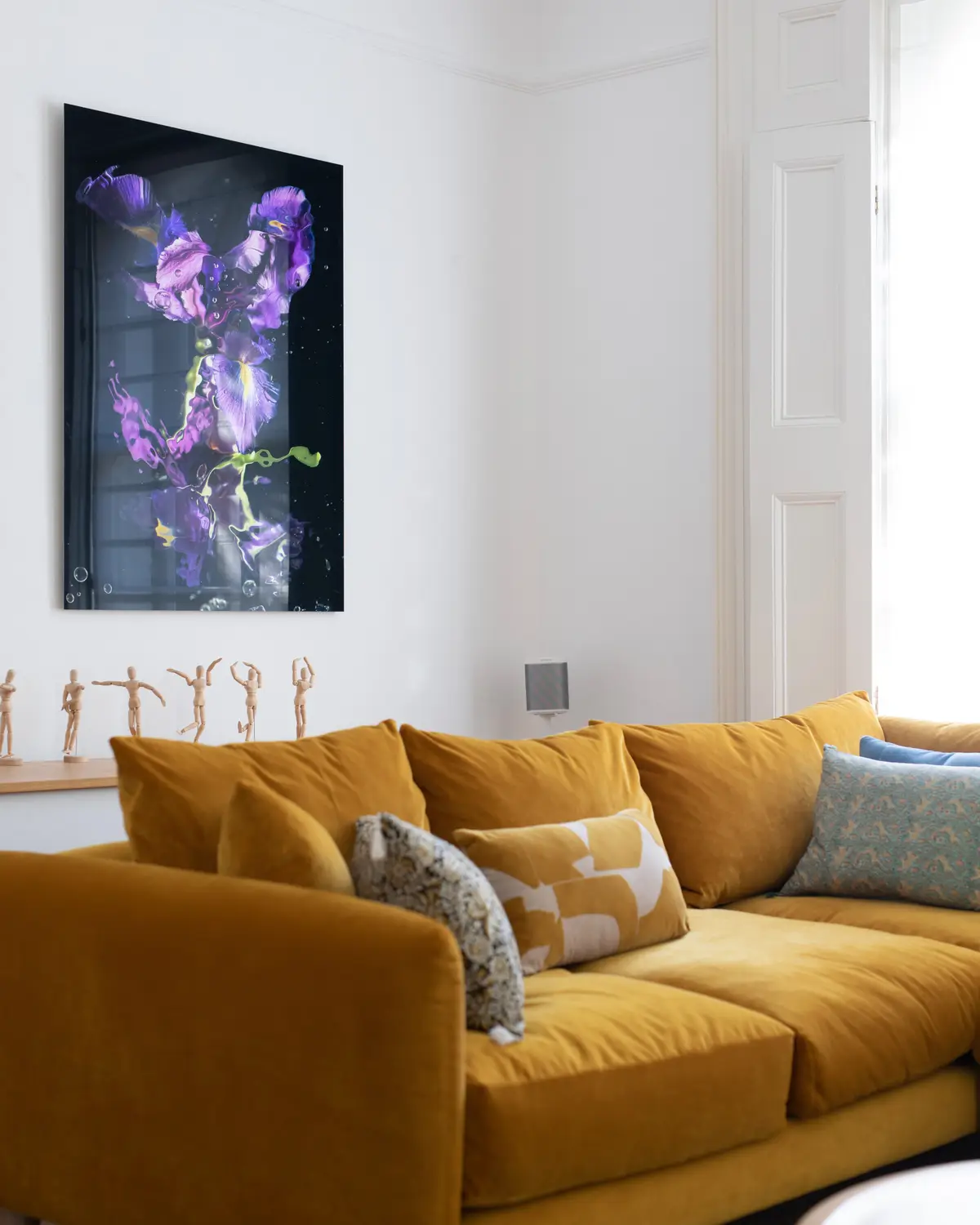 Mustard sofa with cushions under a large floral artwork