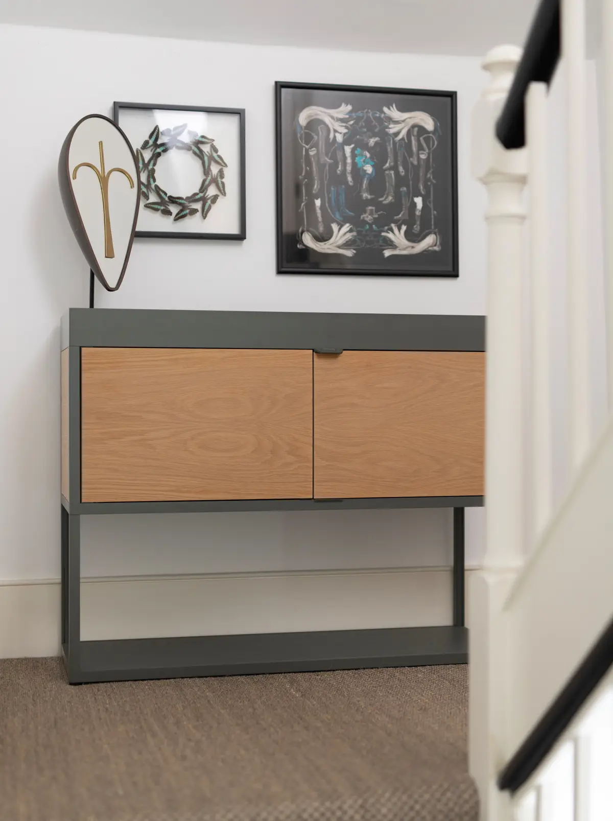 Slim oak and black metal console with framed artwork