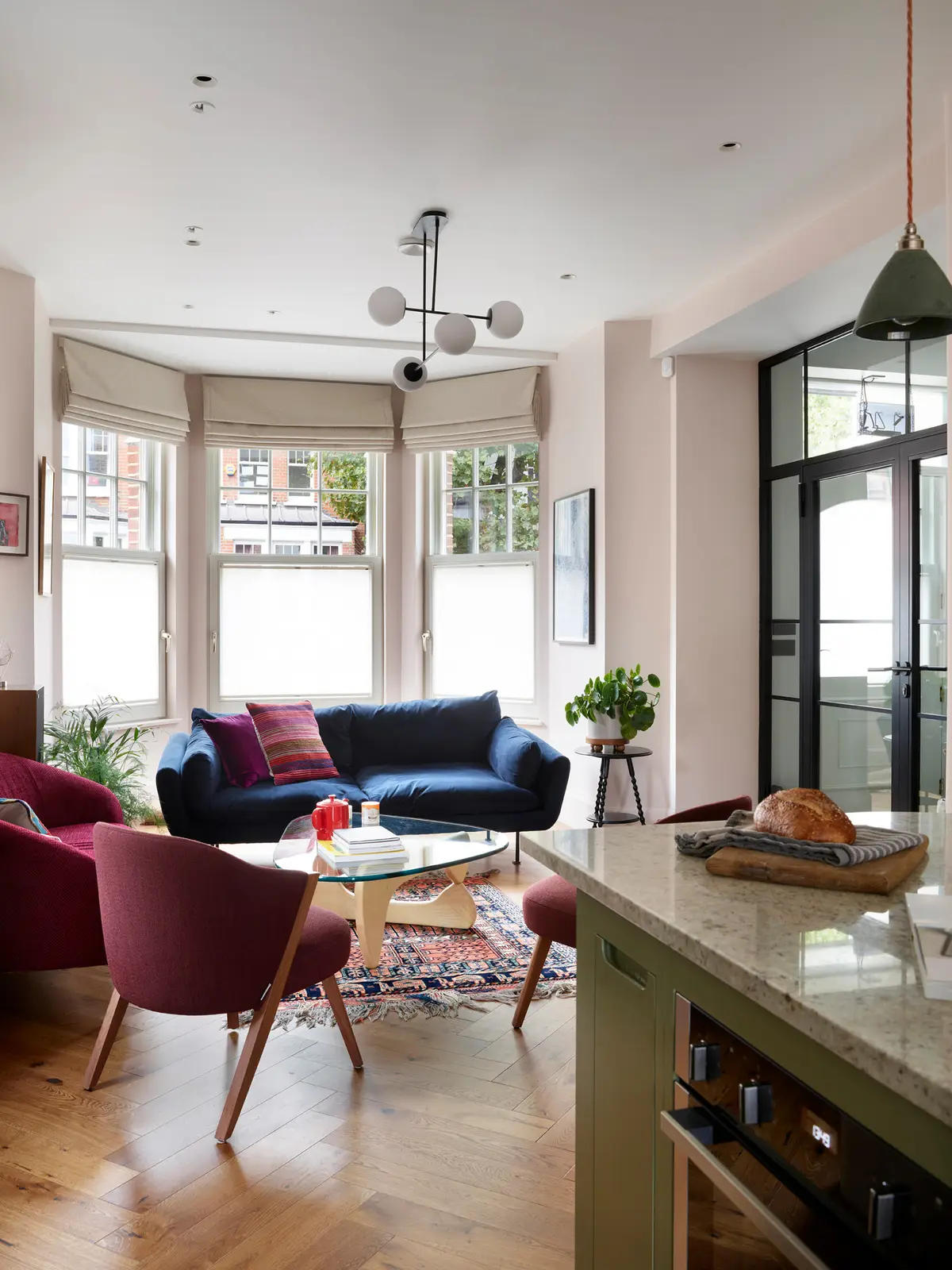 Living room with a navy velvet sofa, red armchair and black-framed glazed doors, Muswell Hill