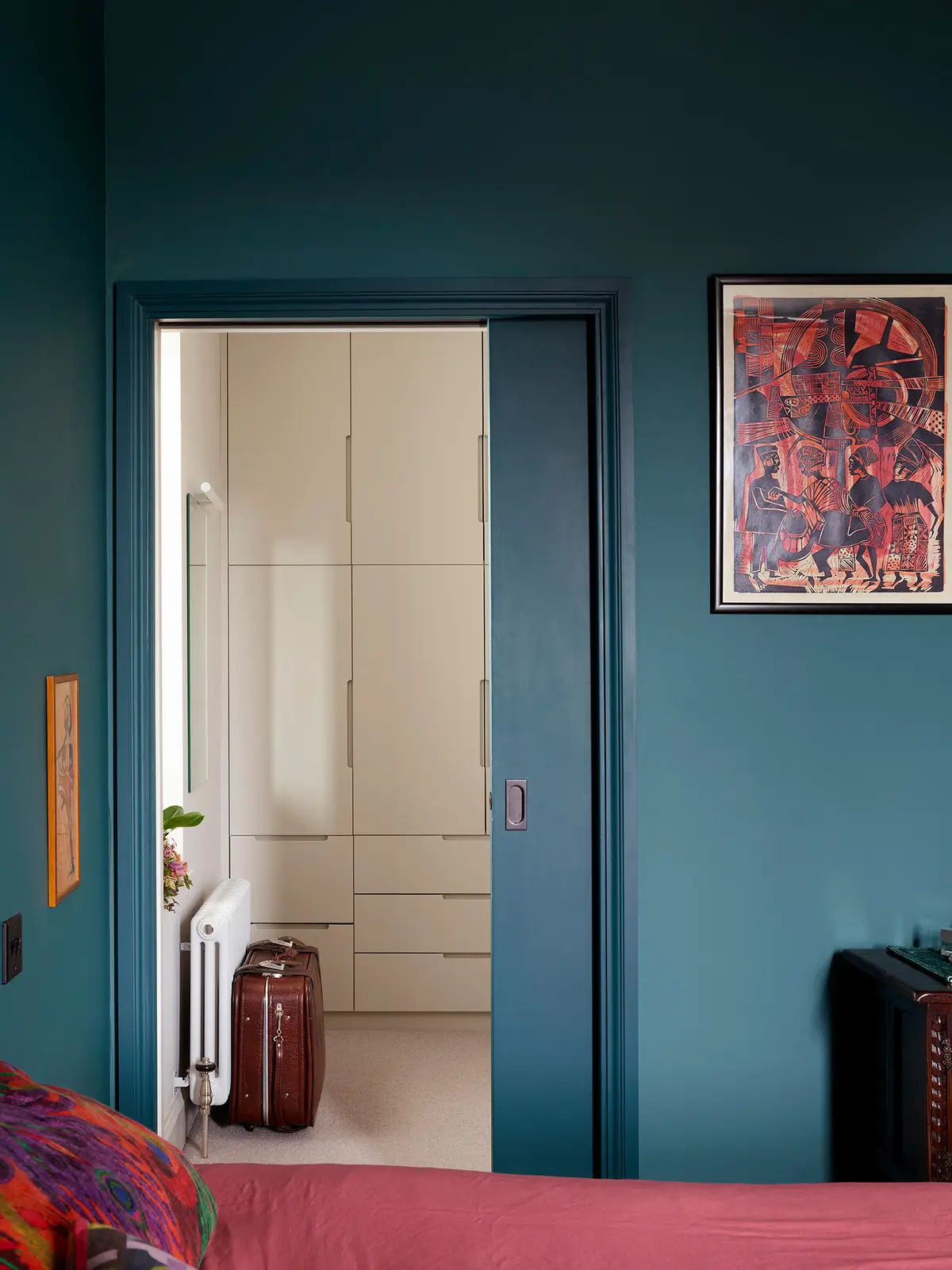 Teal sliding door beside cream fitted wardrobes
