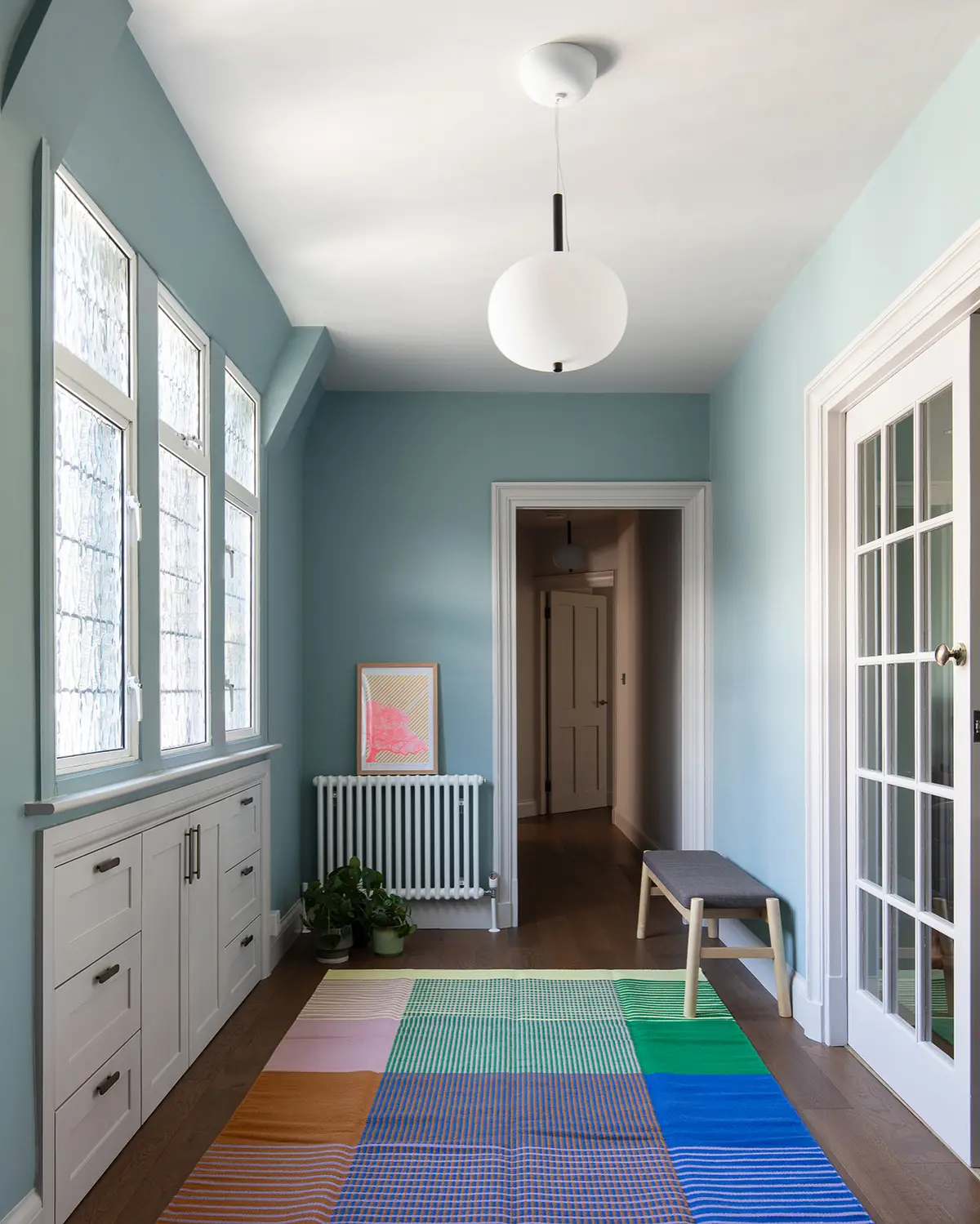 Pale blue hallway with white panelled doors and a slim bench, Hampstead