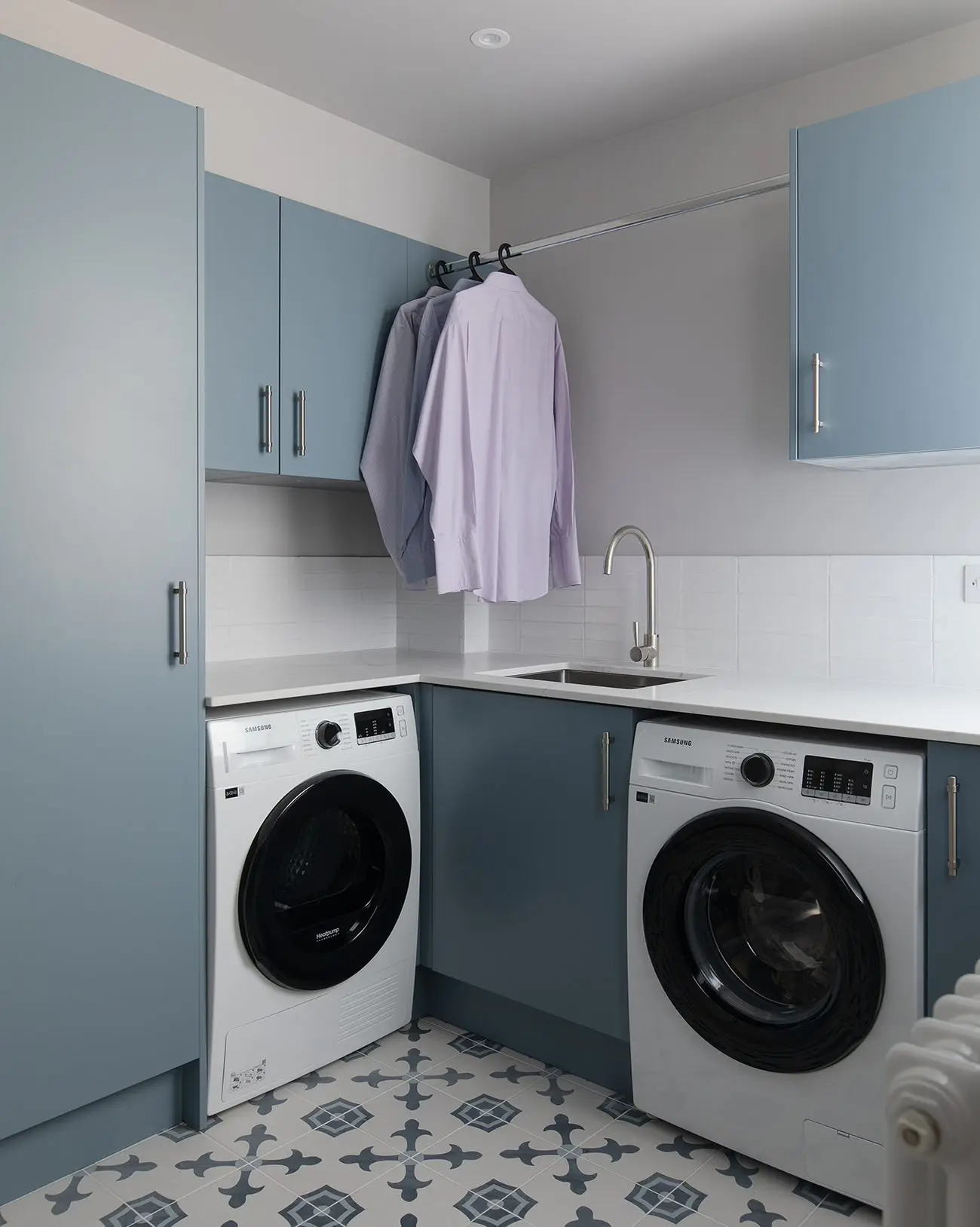 Utility room with stacked washer and dryer and blue-grey cabinetry