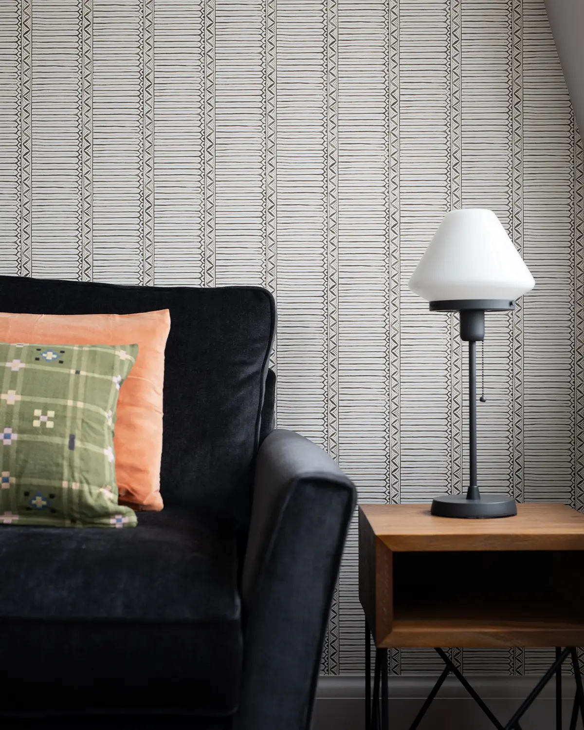 Reading corner with a black armchair, orange cushion and table lamp