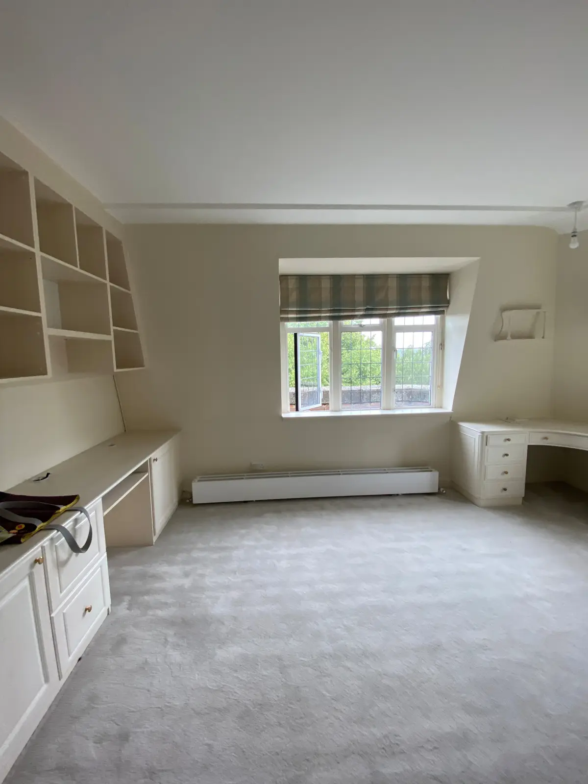 Unfurnished room with cream built-in units and carpet beneath a window