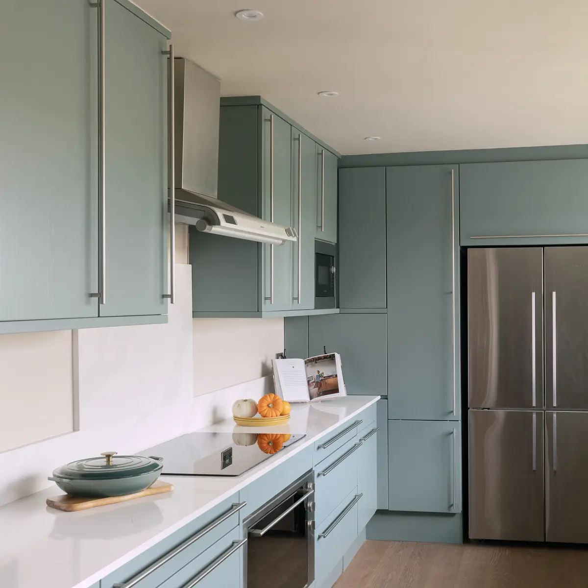 Sage green kitchen with tall fridge housing and built-in oven