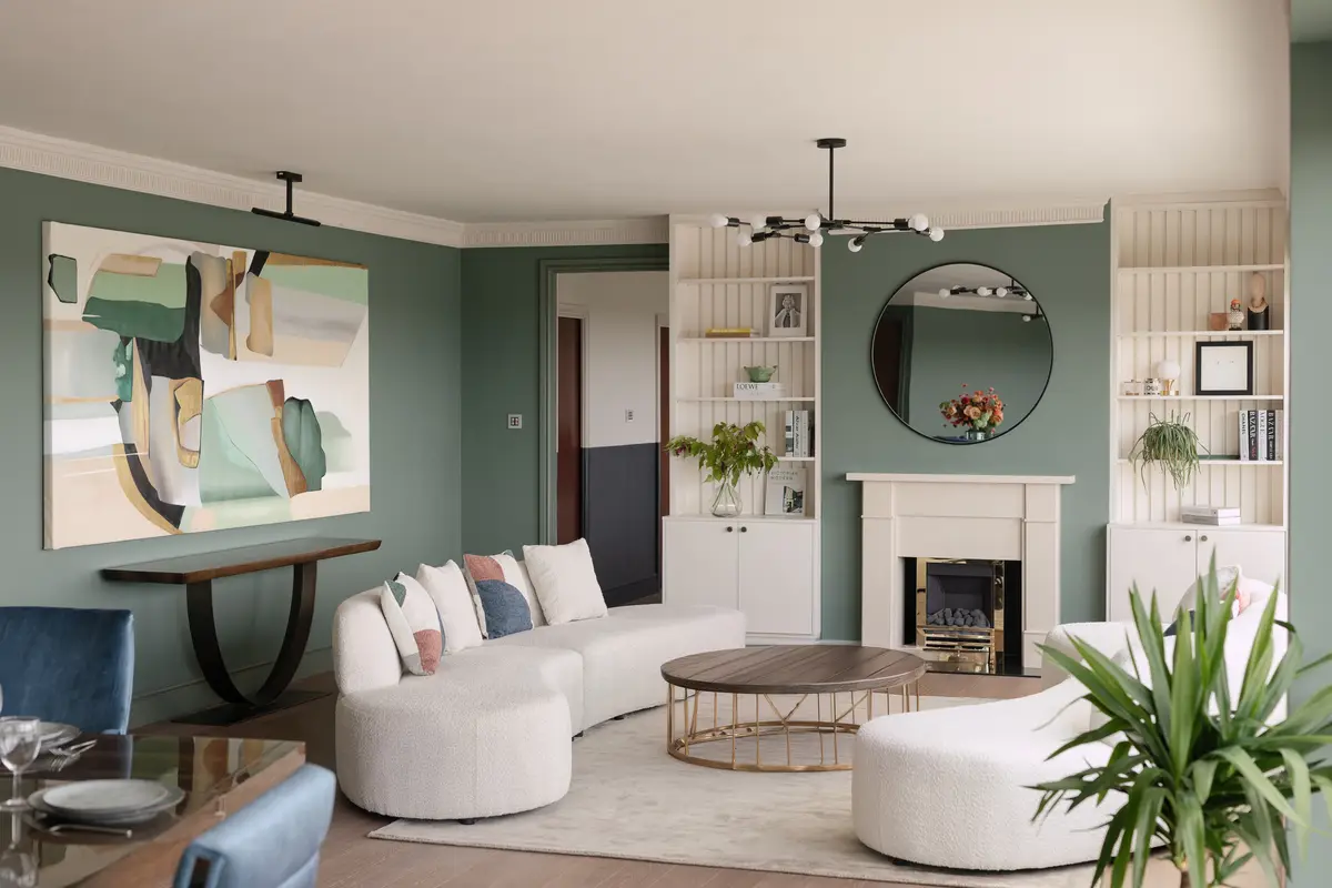 Living area with a curved white sofa, sage walls and a fireplace