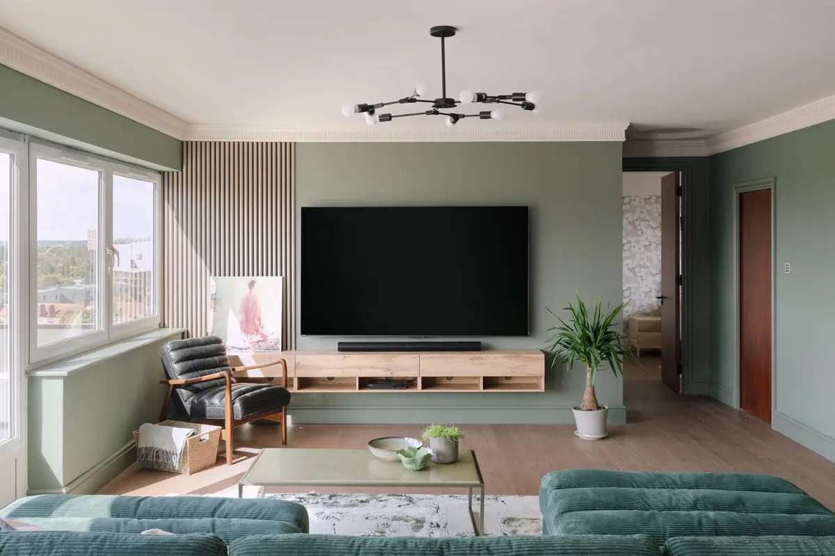 Penthouse living room with a teal sofa and wide windows over the treetops, Highgate