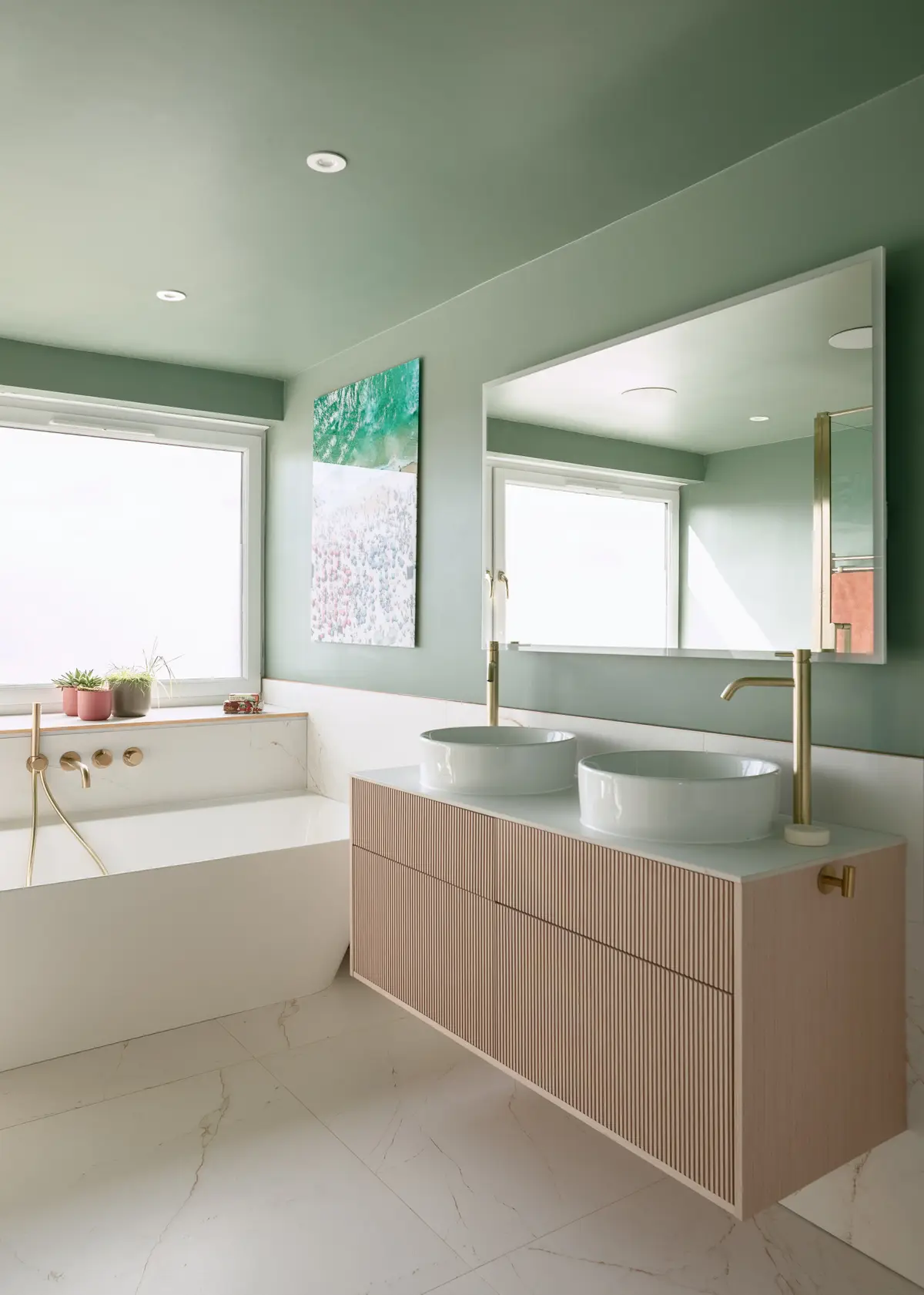 Bathroom with twin stone basins, brass taps and green walls