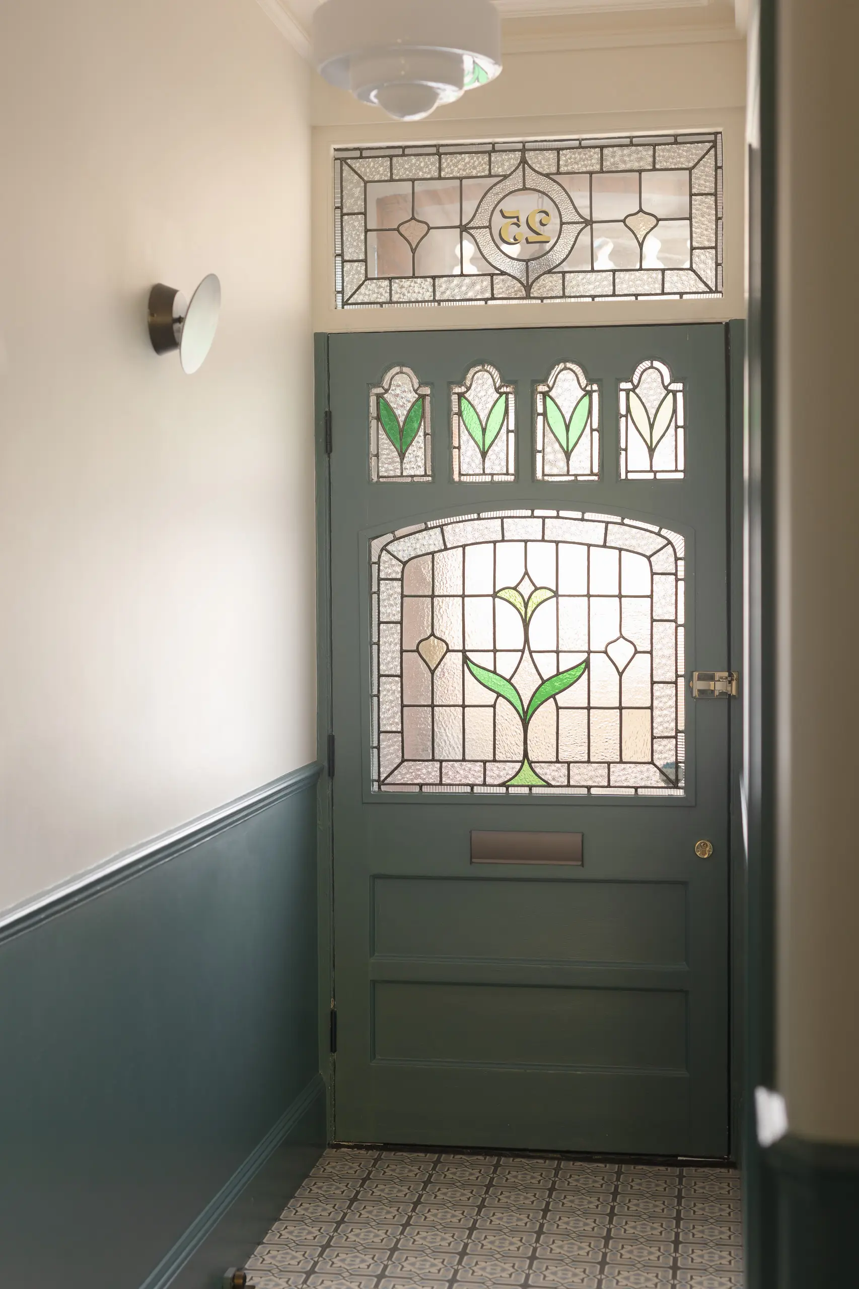 Victorian front door with stained-glass panels above green-painted panelling