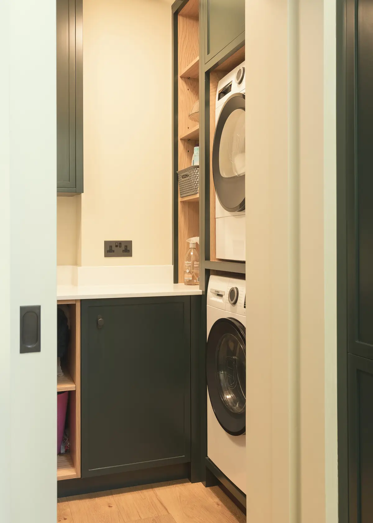 Utility cupboard with a washing machine behind deep green doors