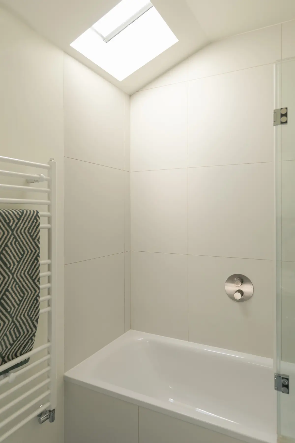 Bright bathroom with white tiles and a heated towel rail